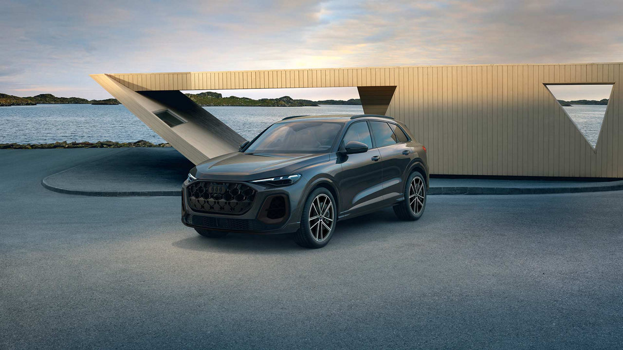 Femme se tenant debout, à gauche d’une Audi RS5 Sportback 2023 de couleur gris espace.