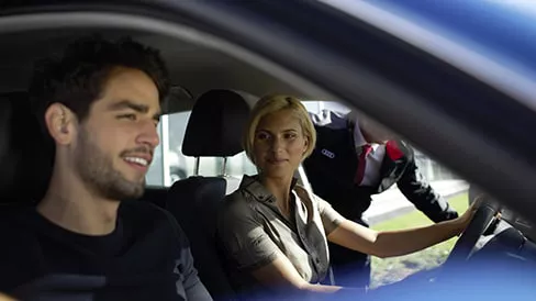 A man and a woman sitting in an Audi vehicle at a dealership. 