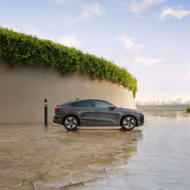 Side-view of a grey Audi Q6 Sportback e-tron parked and charging.