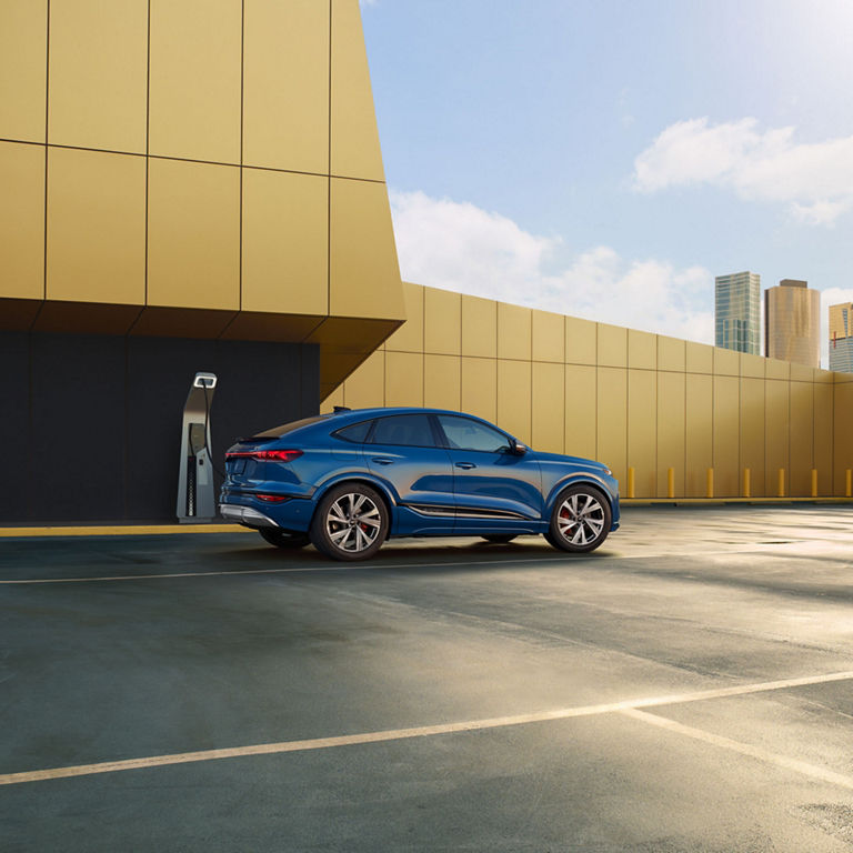 Three-quarter side view of a blue Audi SQ6 Sportback e-tron parked and charging.