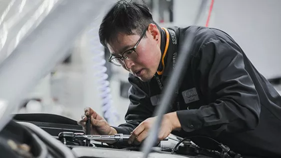 Gros plan d'un technicien Audi travaillant sous le capot d'un véhicule Audi.