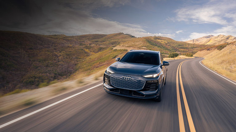 A gray Audi Q8 e-tron accelerating up a mountain road.