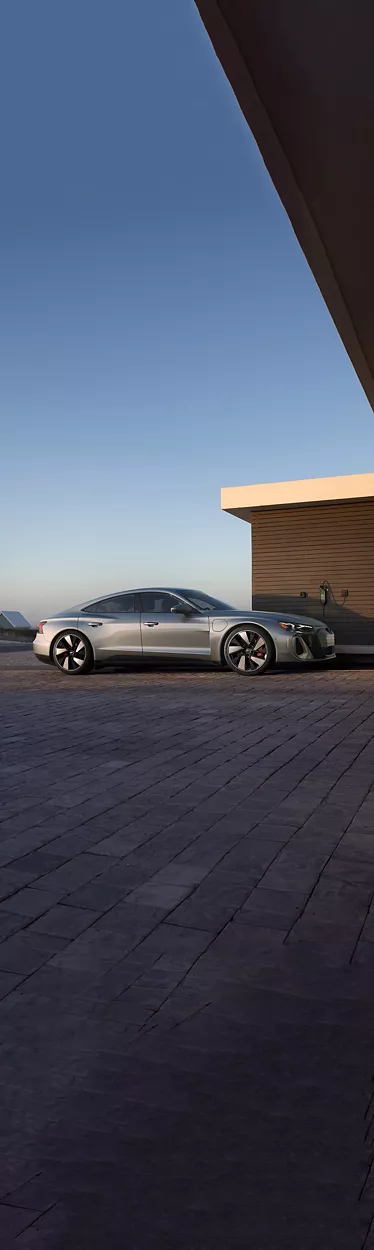 Side view of an Audi Q8 e-tron charging in front of a home. 