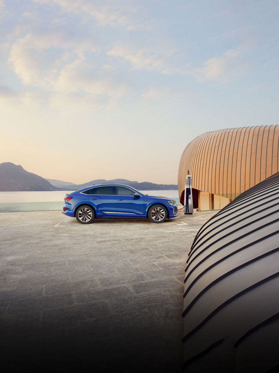 Three-quarter front profile of an Audi SQ8 Sportback e-tron parked and charging on a driveway.