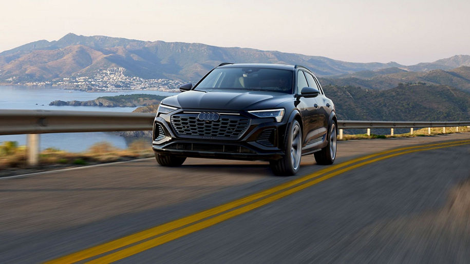 Three-quarter front profile of an Audi Q8 Sportback e-tron parked and charging on a driveway.