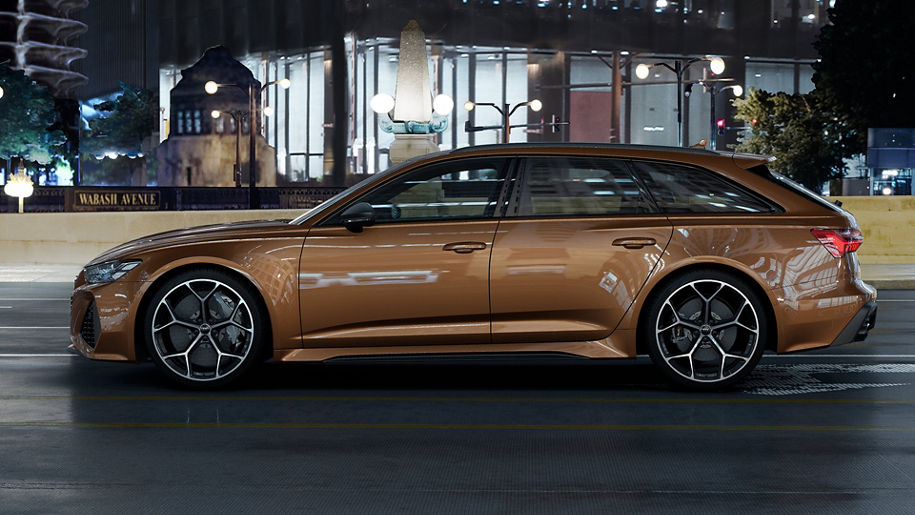 Side profile of a brown Audi RS 6 in motion on a city street. 