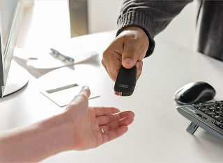Close up of two hands; one giving Audi vehicle key to the receiving open hand