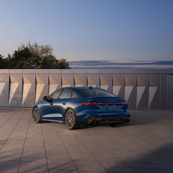Three-quarter rear view of the Audi S5 parked in front of a modern building.