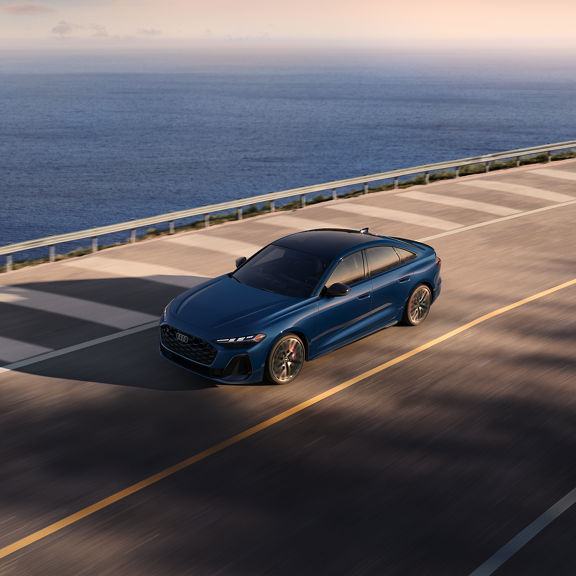Aerial front view of the Audi S5 accelerating on an oceanside road.