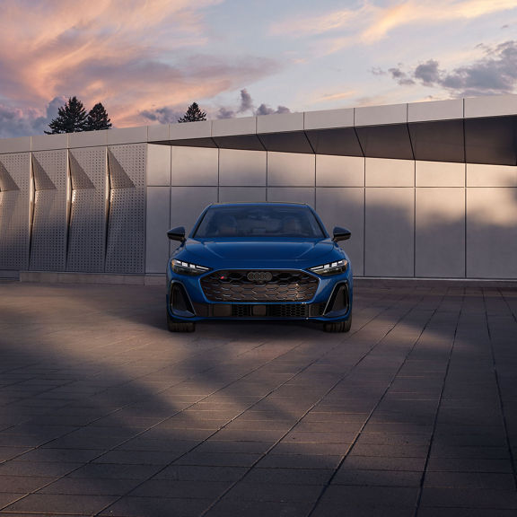 Front profile of the Audi S5 parked by a modern building.