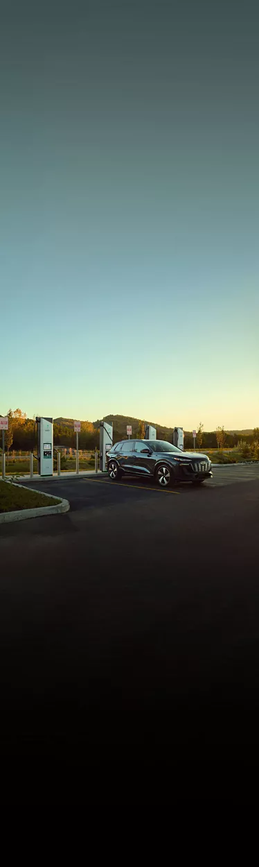 Three-quarter side view of an Audi e-tron vehicle charging at an Electrify America station.