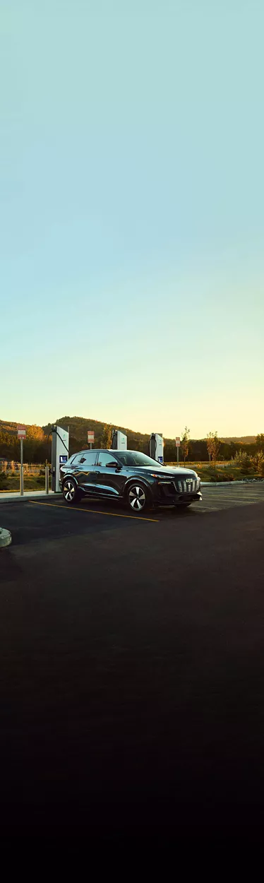 Three-quarter side view of an Audi e-tron vehicle charging at an Electrify America station.