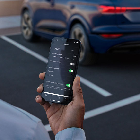 Person holding a phone, showing the climate control options in the myAudi app.
