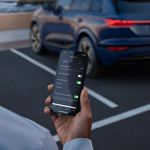 Person holding a phone, showing the climate control options in the myAudi app.