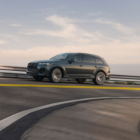 Side view of an Audi SQ7 accelerating on a mountain-side road. 