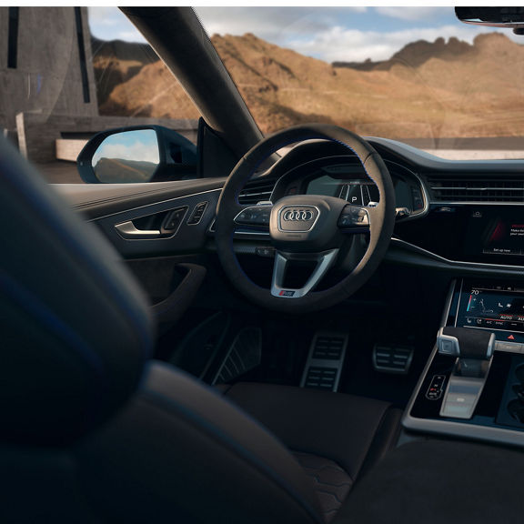 View of the interior cabin showing the steering wheel, dashboard, and center console of the Audi RS Q8.