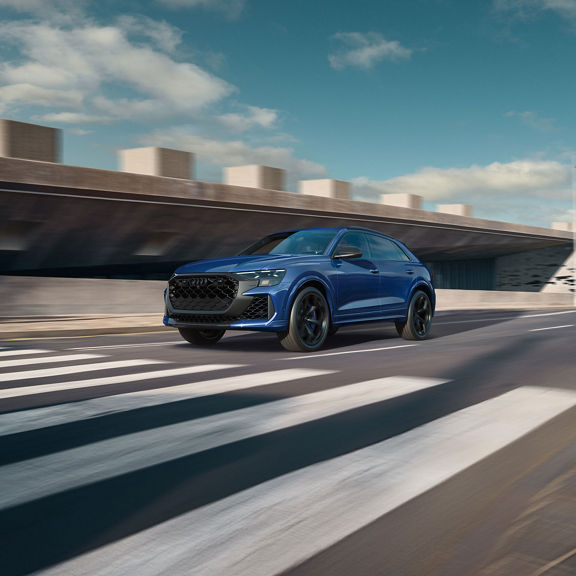 Three-quarter front view of the Audi RS Q8 accelerating on a city road.