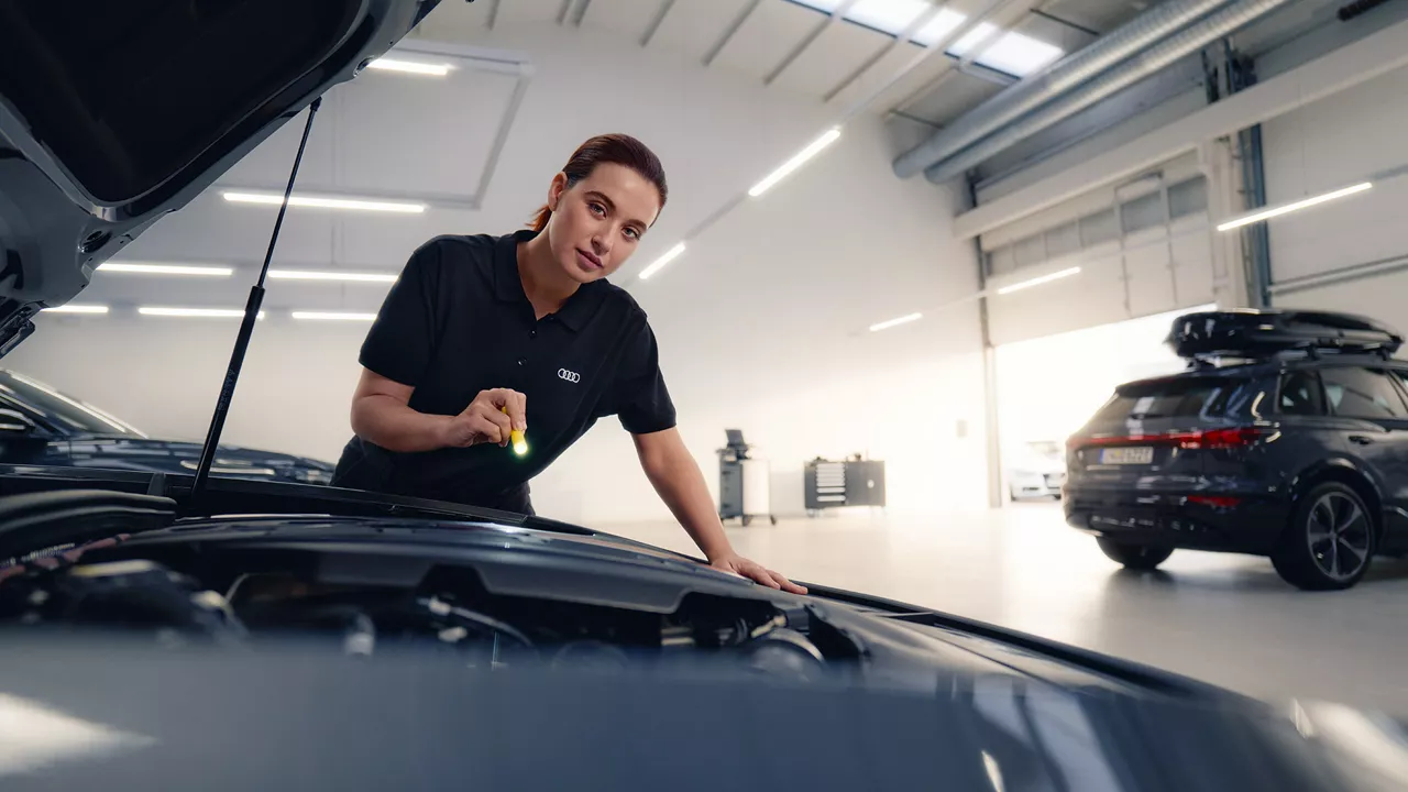 An Audi technician inspecting a vehicle.