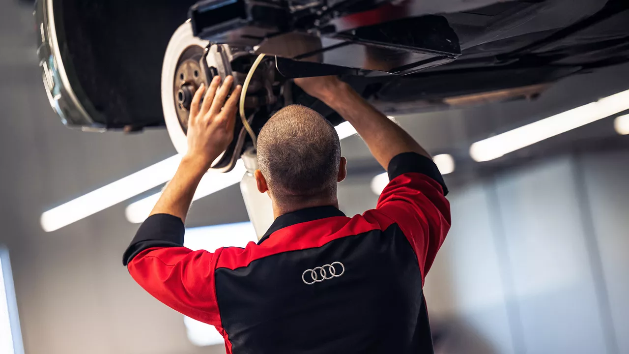 An Audi mechanic working on a vehicle. 