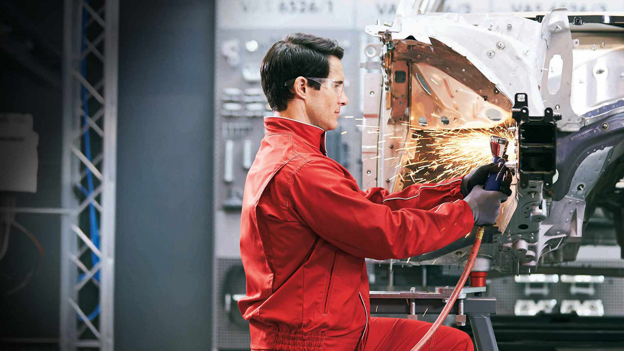 An Audi maintenance employee fixing a vehicle after a collision.