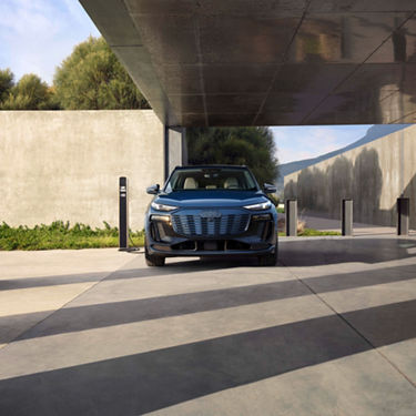 Profil avant d’un Audi Q6 e-tron bleu en recharge stationné.