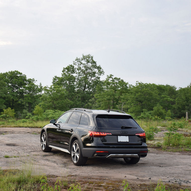 3/4 rear view of the Audi A4 allroad driving down a dirt road.