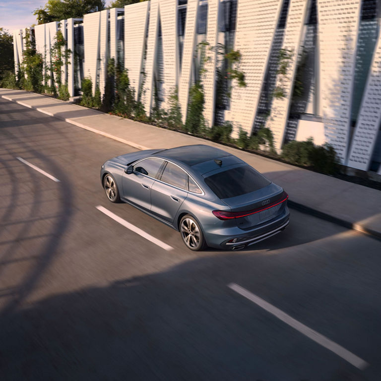 Aerial rear view of the Audi A5 accelerating on a city road.