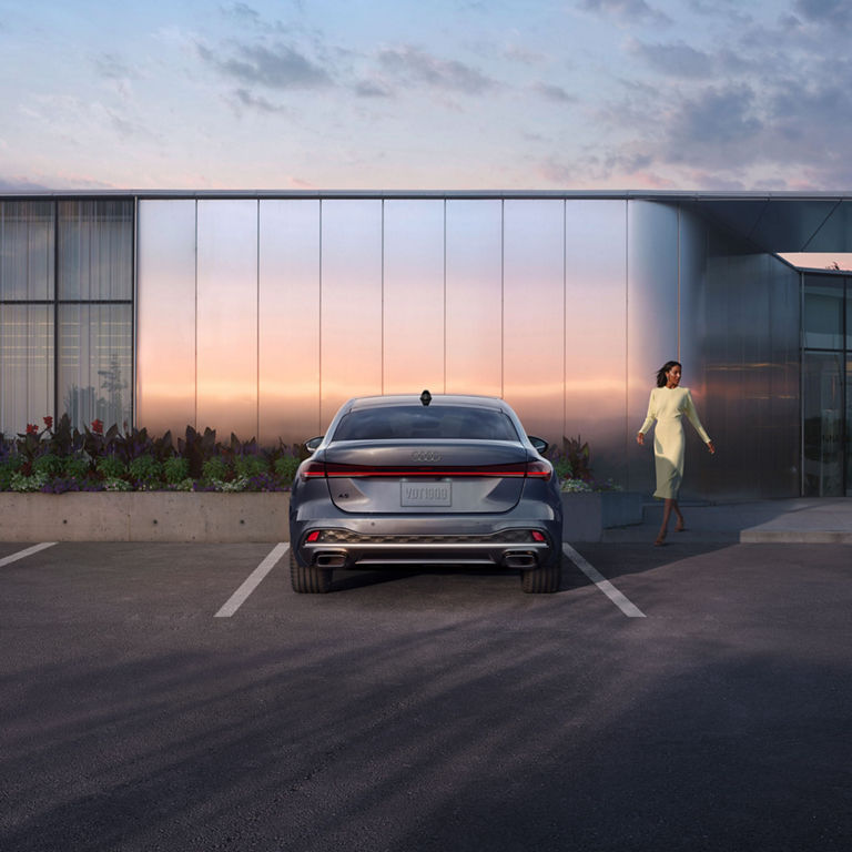 Rear profile of the Audi A5 with a person walking towards the vehicle.
