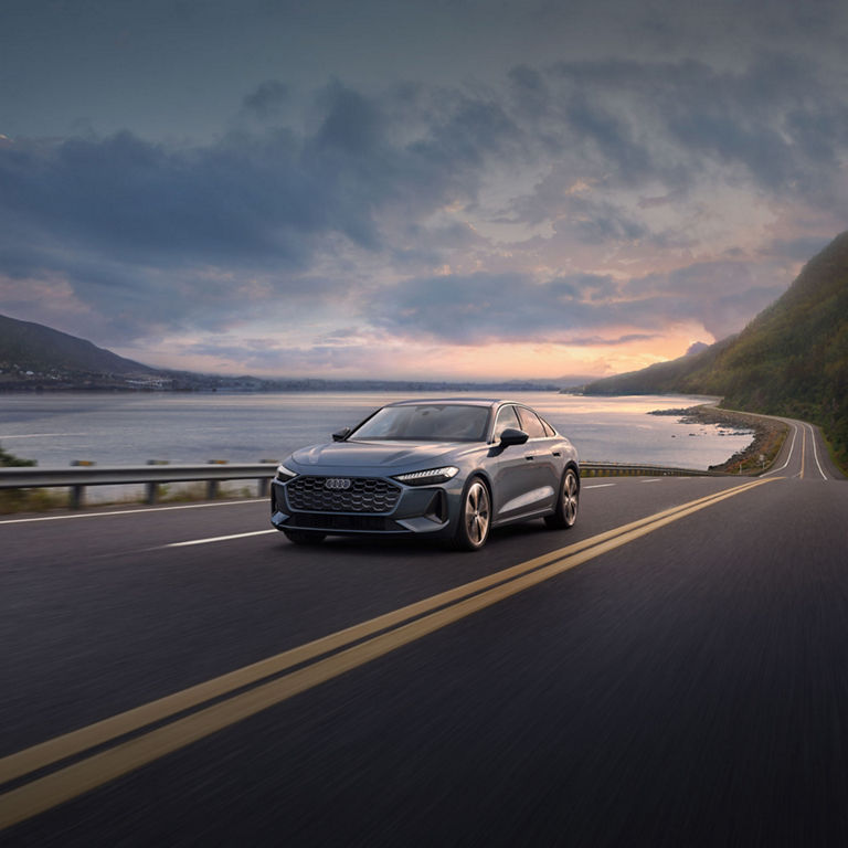 Front view of the Audi A5 accelerating on an oceanside road.