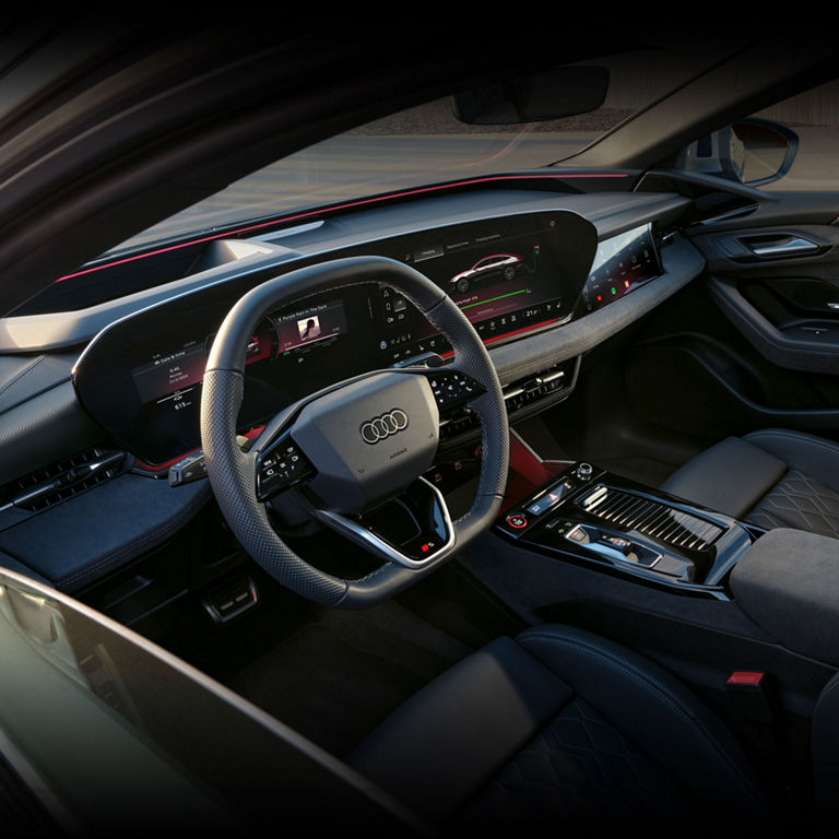 View of the interior cabin of the Audi S6 e-tron, showing the steering wheel, virtual cockpit, and centre console.