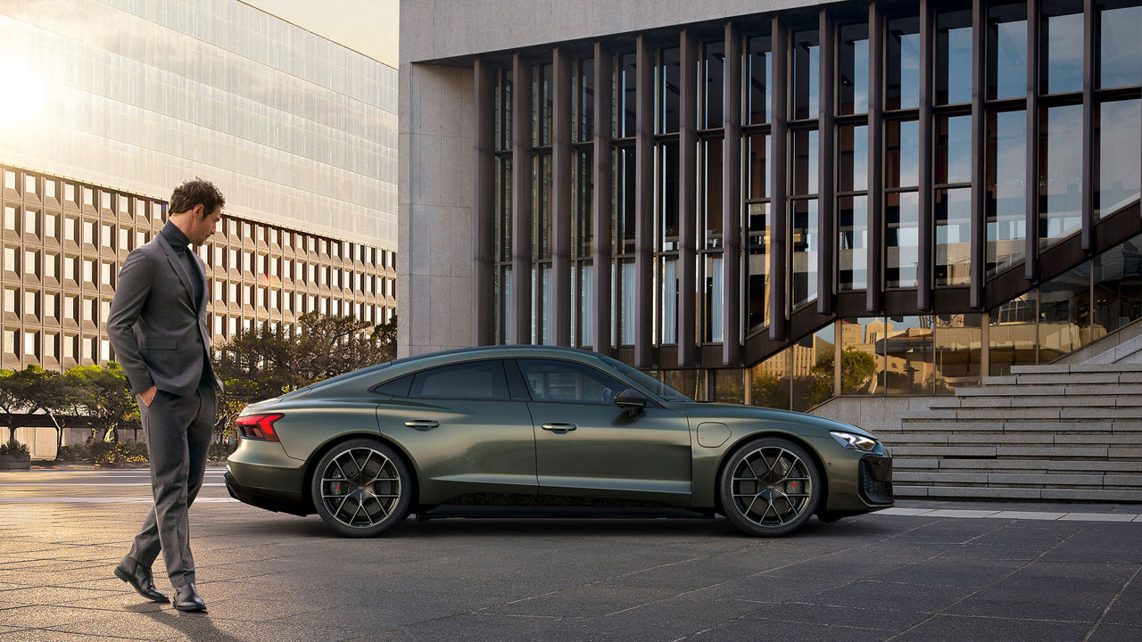 Vue latérale de l'Audi RS e-tron GT garée près d'un bâtiment moderne avec une personne qui passe.