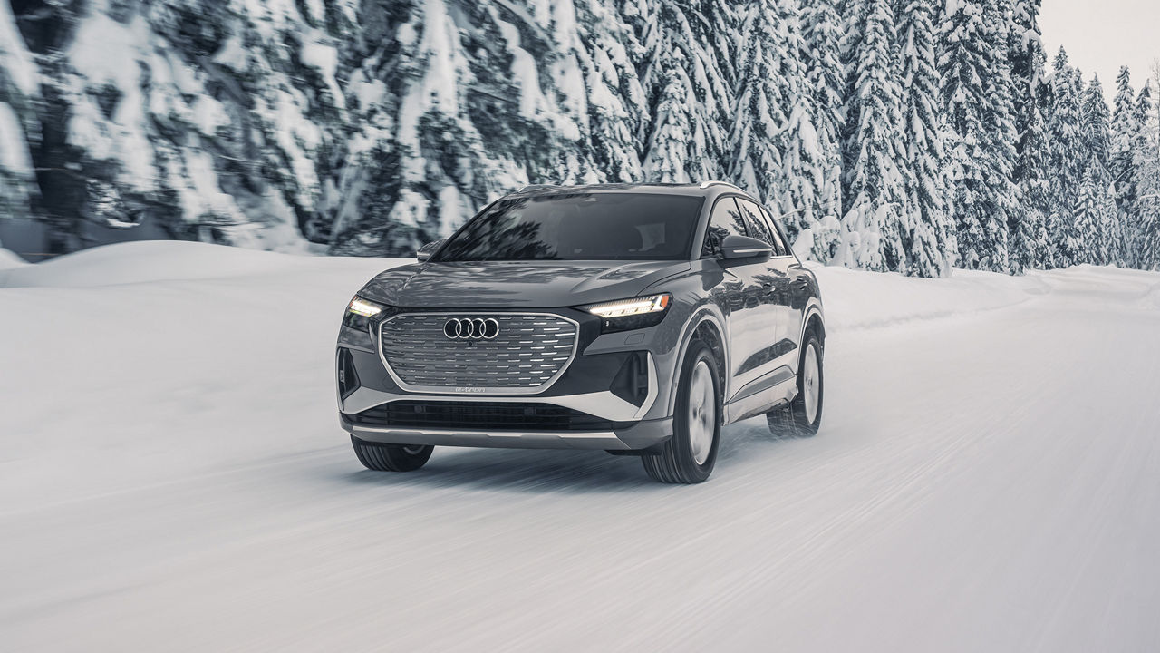 Three-quarter front profile of the Audi Q4 e-tron accelerating on a snowy road.