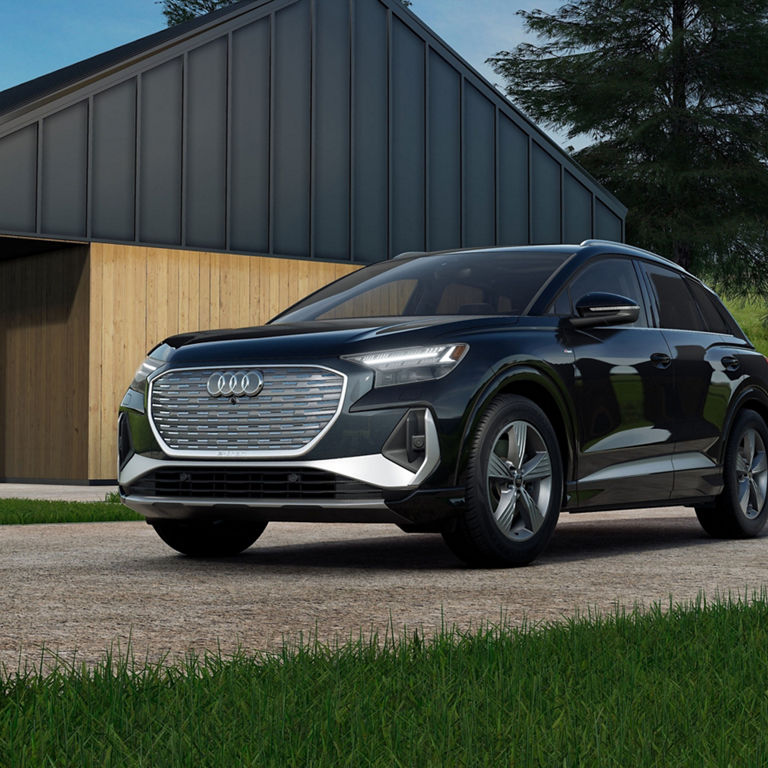 Three-quarter front view of the Audi Q4 e-tron parked in a forest.