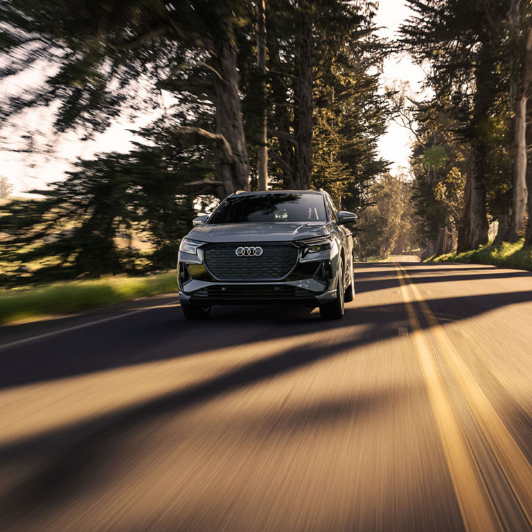 Three-quarter front profile of the Audi Q4 e-tron accelerating on a snowy road.