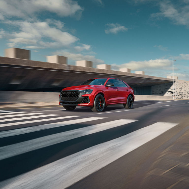 Three-quarter front view of the Audi RS Q8 accelerating on a city road.