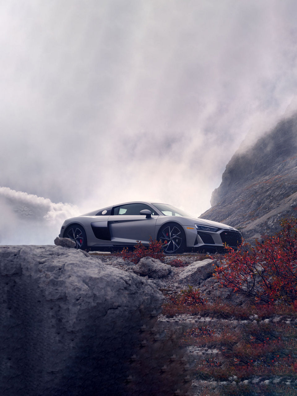 Elevated three-quarter side profile of the Audi R8 Coupé.