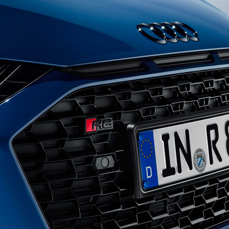 Close-up of the front bumper of the Audi R8 Coupé with black emblems. 