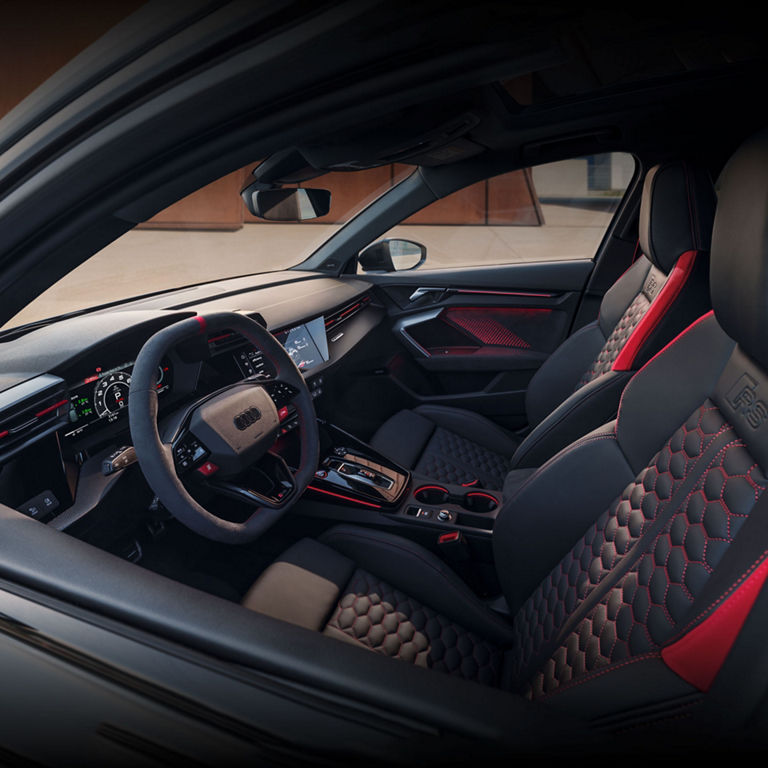 Vue intérieure de l'habitacle de l'Audi RS 3, montrant les sièges sport avant, le volant et la console centrale.