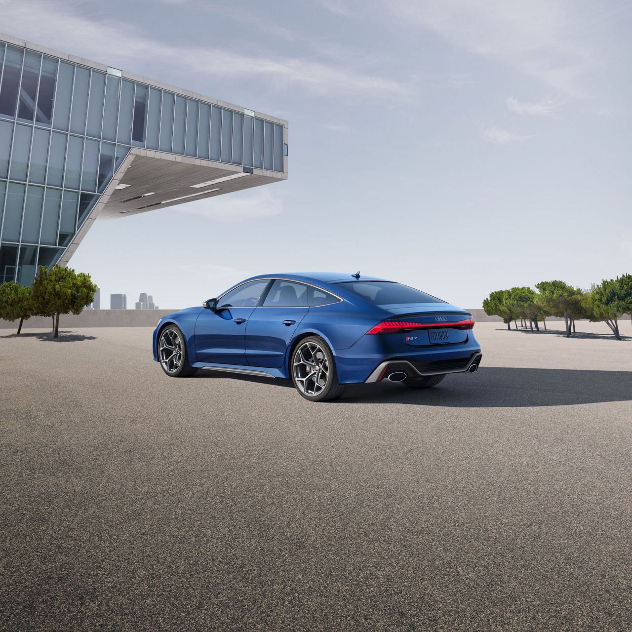 Vue avant de 3/4 de l’Audi RS 7 Performance stationnée à côté d’un bâtiment moderne.