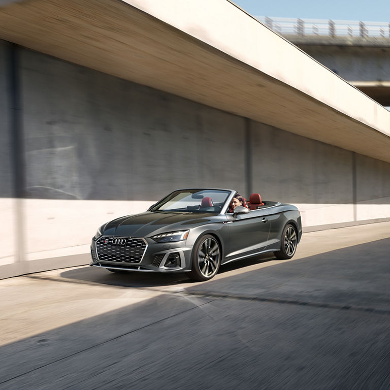 Three-quarter front view of a woman driving the Audi S5 Cabriolet.