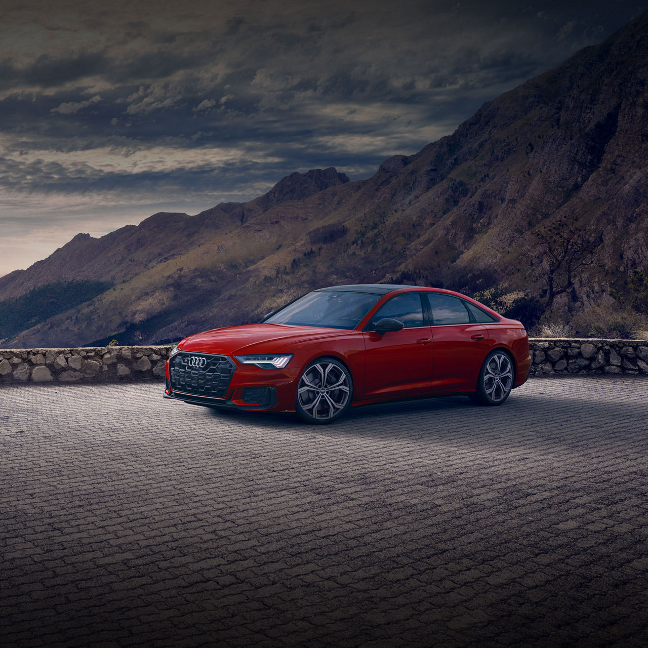 Three-quarter side profile of the Audi S6 Sedan parked by a mountain range.
