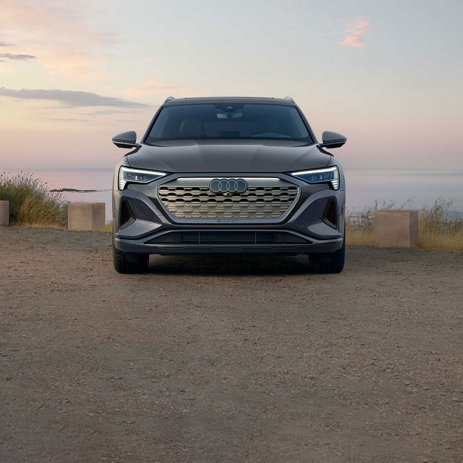 Front profile of a grey Audi Q8 e-tron parked by a waterfront.