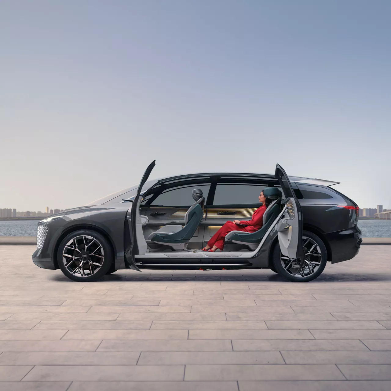 Side view of a woman sitting in the urbansphere concept car with the doors open.