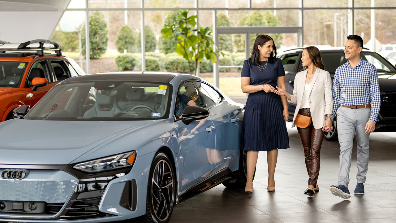 Audi employee leading two owners to their Audi.