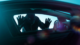 Close-up of a person in a mask trying to break into a vehicle. 