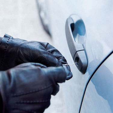 Close-up of an individual's hands attempting to pick a vehicle door lock.