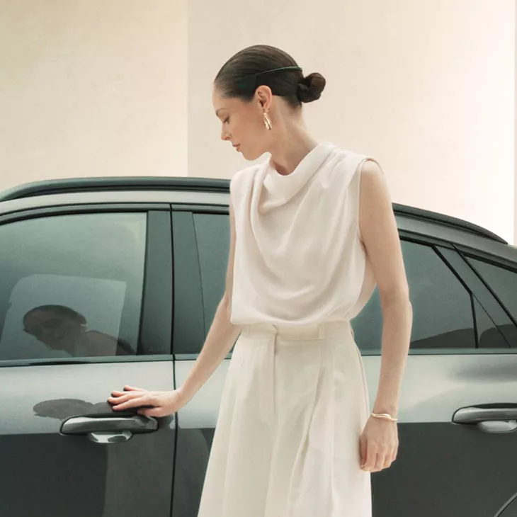 Portrait of supermodel Coco Rocha posing next to an Audi Q8 e-tron. 