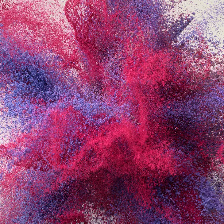 A 3D render of an explosion of pink and purple particles. 