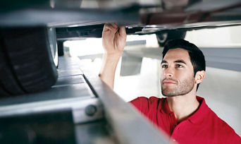 An Audi mechanic servicing the underside of a vehicle. 