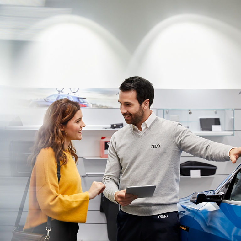 Audi employee explaining the Audi Financial Services Newcomer program to a customer.